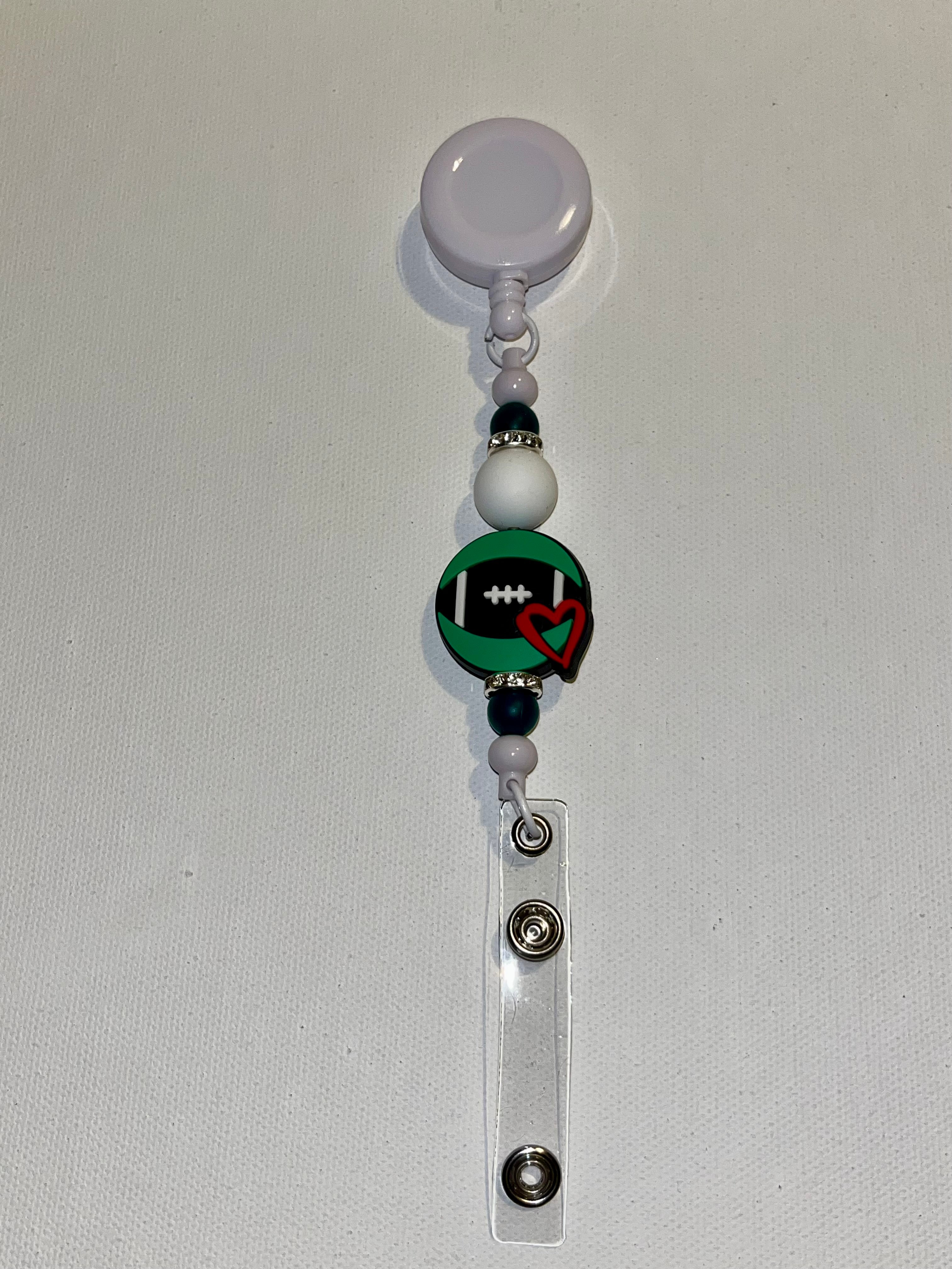 White Badge Reel w/Football Charm & Red Heart, Black, Green & Rhinestone Accents